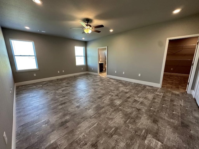 unfurnished bedroom featuring dark hardwood / wood-style flooring, ensuite bath, a spacious closet, and ceiling fan