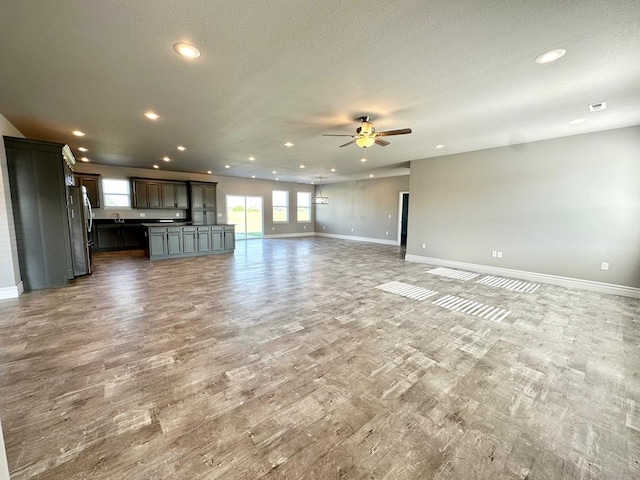 unfurnished living room with hardwood / wood-style flooring, ceiling fan, and a textured ceiling