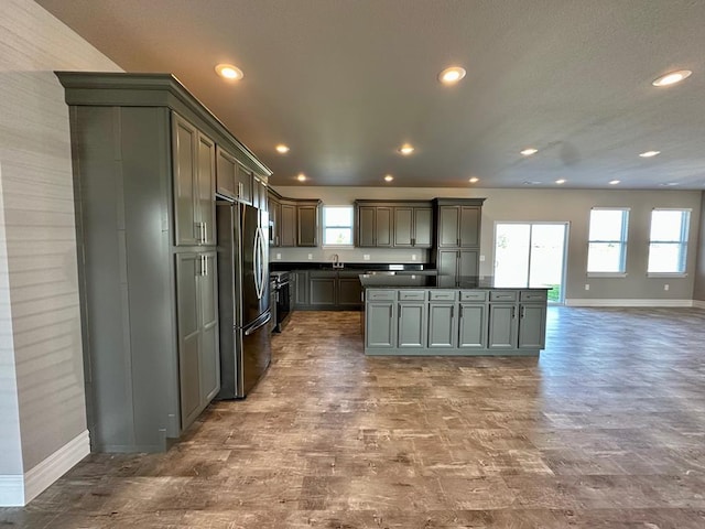 kitchen with gray cabinetry, stainless steel fridge, a center island, and sink