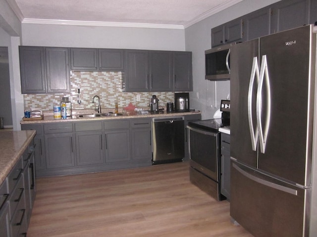 kitchen featuring sink, decorative backsplash, ornamental molding, light hardwood / wood-style floors, and stainless steel appliances