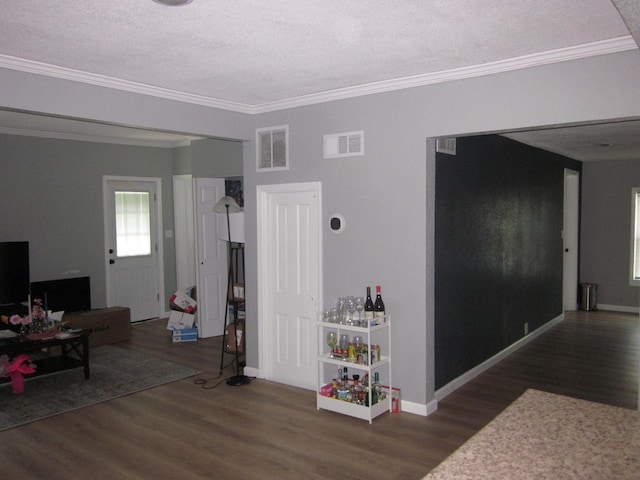 interior space featuring a textured ceiling, crown molding, and dark wood-type flooring