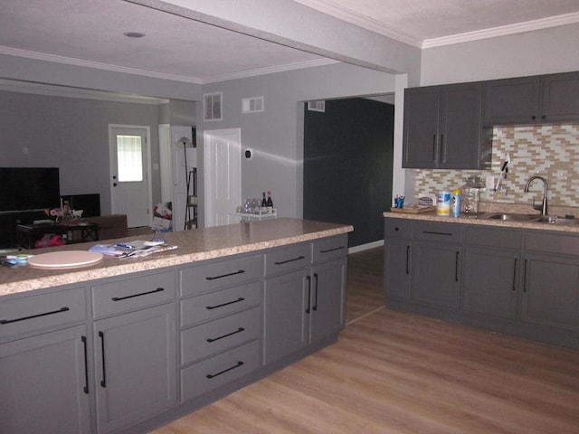 kitchen featuring sink, light hardwood / wood-style flooring, gray cabinets, decorative backsplash, and ornamental molding