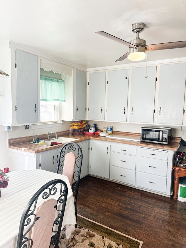 kitchen with dark wood finished floors, ceiling fan, light countertops, white cabinetry, and stainless steel microwave