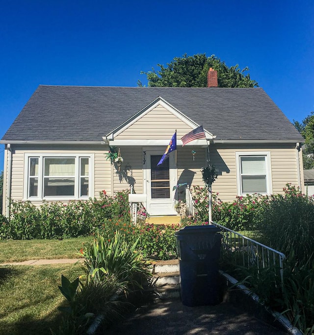 bungalow-style home with roof with shingles and a chimney