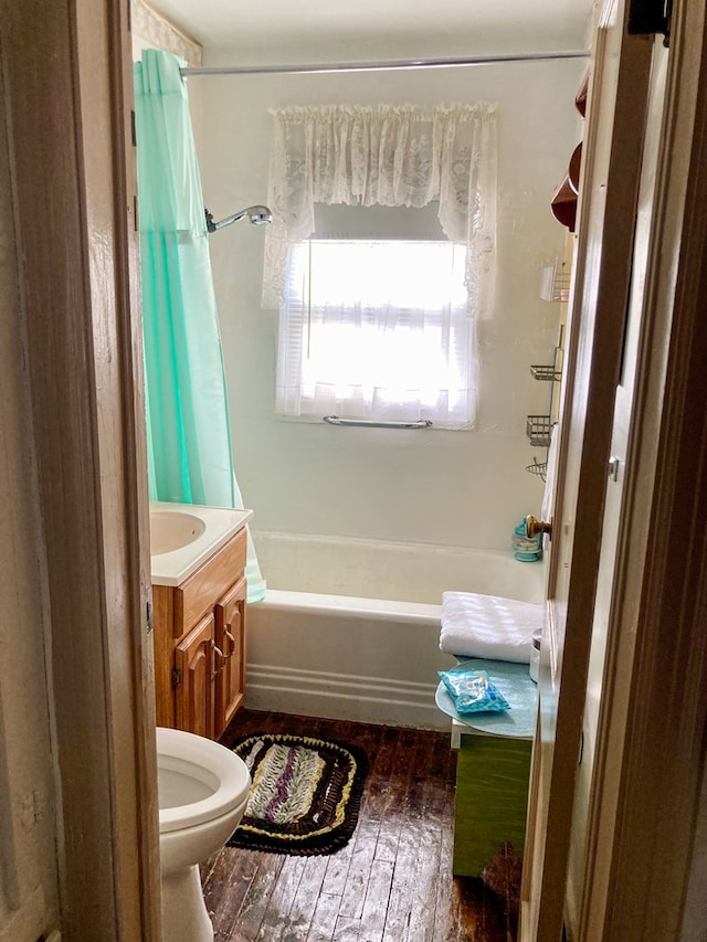 bathroom featuring toilet, vanity, shower / tub combo with curtain, and hardwood / wood-style flooring