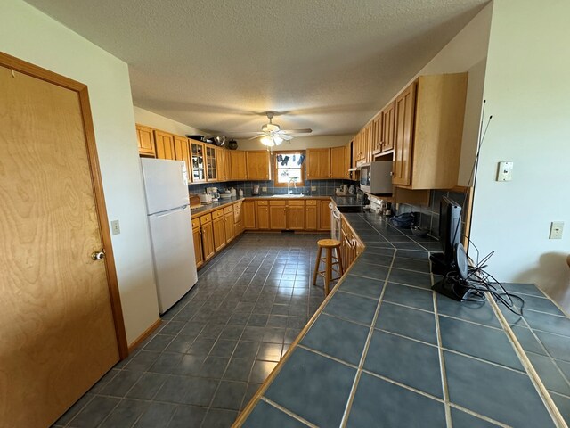 14695 Motter Hill Rd, Kirksville, MO 63501 - kitchen with freestanding refrigerator, tile counters, a sink, tasteful backsplash, and ceiling fan