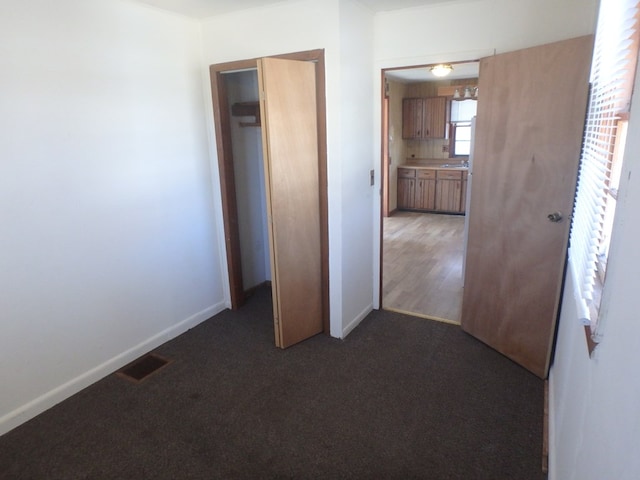 unfurnished bedroom featuring dark colored carpet and a closet