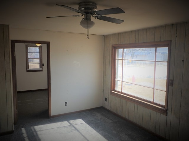 carpeted empty room with wooden walls and ceiling fan