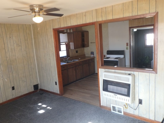 kitchen with wood walls, sink, ceiling fan, white range with electric stovetop, and heating unit