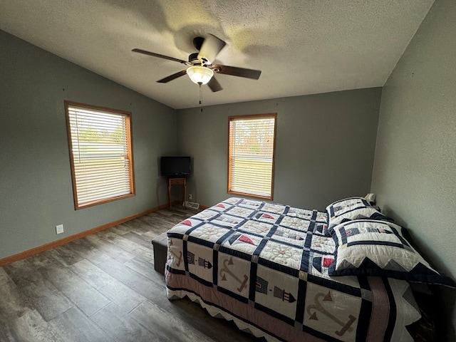 bedroom with ceiling fan, wood-type flooring, a textured ceiling, and multiple windows