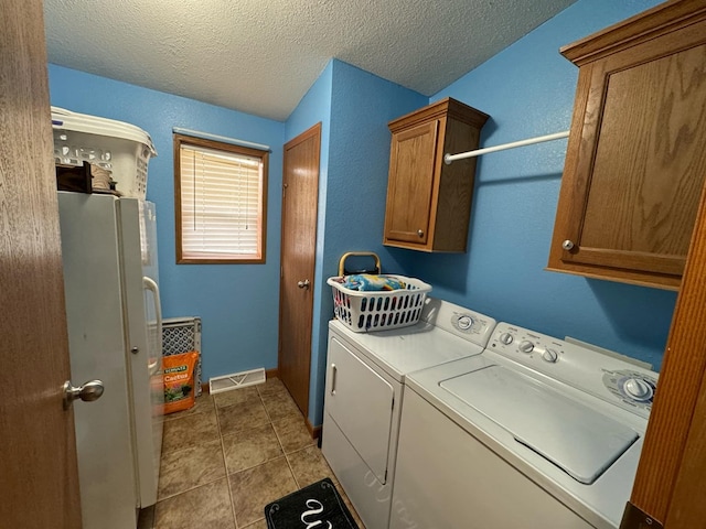 laundry room with washer and clothes dryer, light tile patterned flooring, cabinets, and a textured ceiling