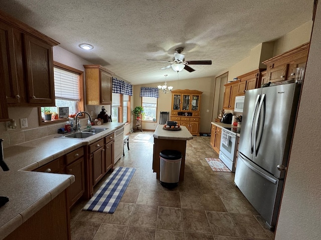 kitchen featuring ceiling fan with notable chandelier, white appliances, vaulted ceiling, sink, and a center island