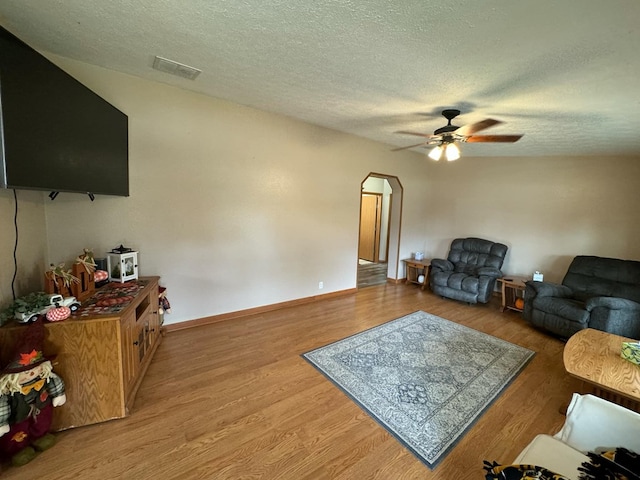 living room with wood-type flooring, a textured ceiling, and ceiling fan