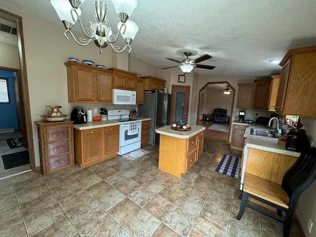 kitchen featuring a center island, sink, hanging light fixtures, white appliances, and ceiling fan with notable chandelier