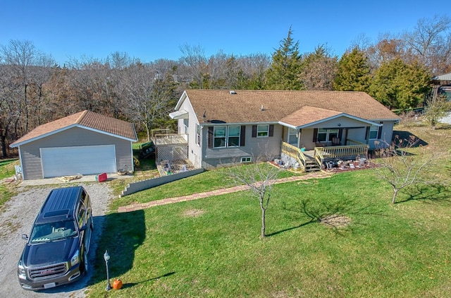 view of front of home featuring covered porch, a garage, an outbuilding, and a front yard