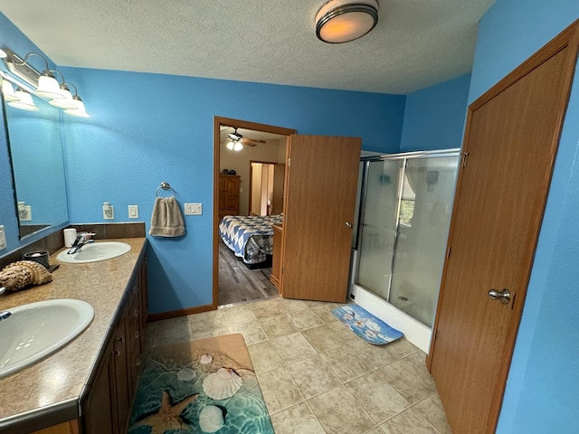 bathroom with vanity, ceiling fan, an enclosed shower, and a textured ceiling