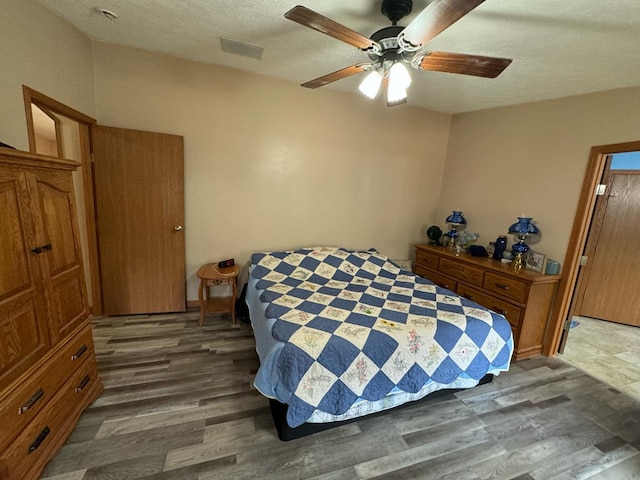 bedroom with ceiling fan, dark hardwood / wood-style flooring, and a textured ceiling