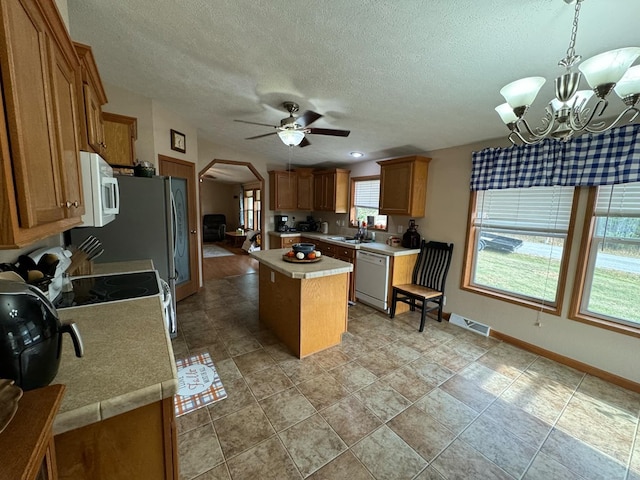 kitchen with dishwasher, sink, hanging light fixtures, a kitchen island, and ceiling fan with notable chandelier