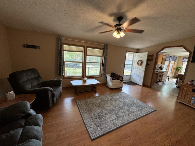 living room featuring ceiling fan, wood-type flooring, and a textured ceiling