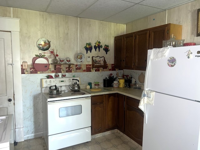 110 Van Buren St, Browning, MO 64630 - kitchen featuring white appliances, light countertops, a paneled ceiling, light flooring, and wood walls