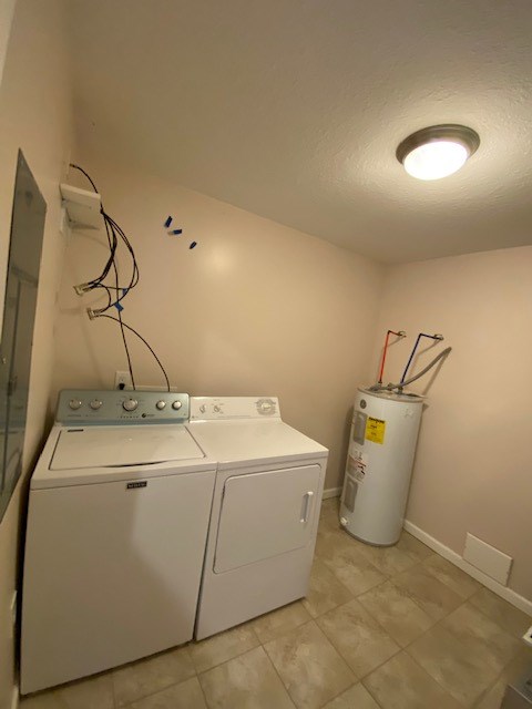 clothes washing area featuring independent washer and dryer, electric water heater, and a textured ceiling