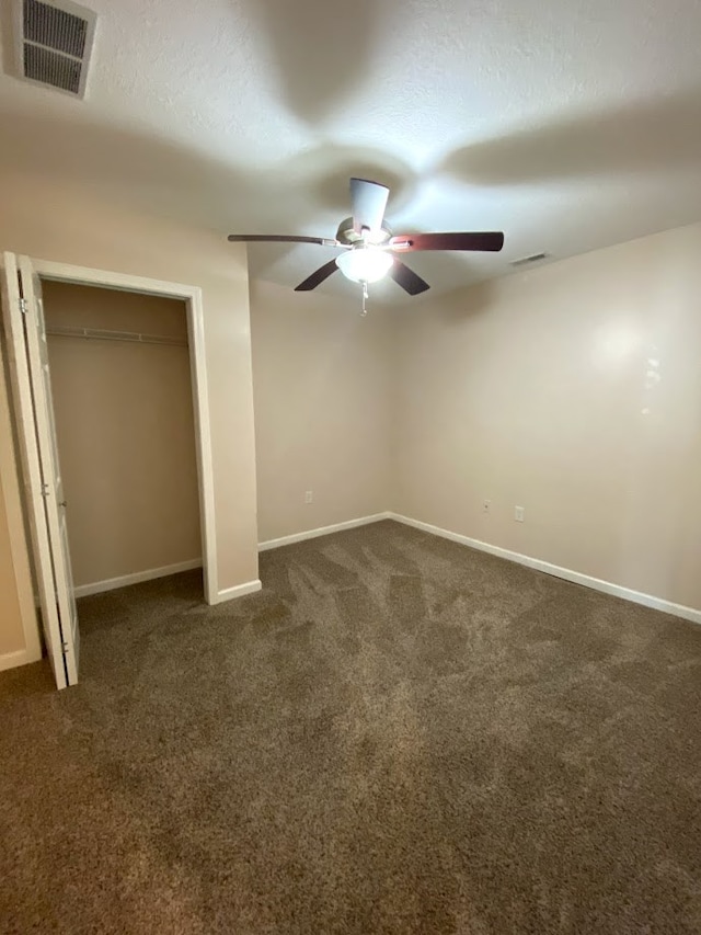 unfurnished bedroom with ceiling fan and dark carpet