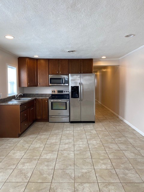 kitchen featuring a textured ceiling, stainless steel appliances, ornamental molding, and sink