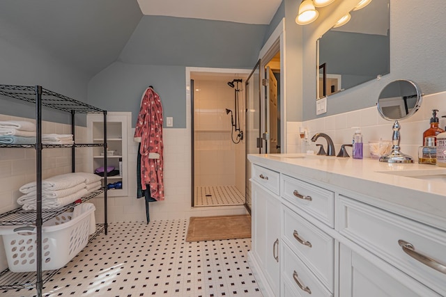 bathroom featuring vanity, a shower with door, vaulted ceiling, tile patterned flooring, and tile walls