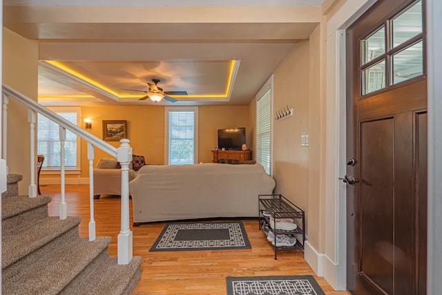 living room featuring hardwood / wood-style floors, a raised ceiling, and ceiling fan