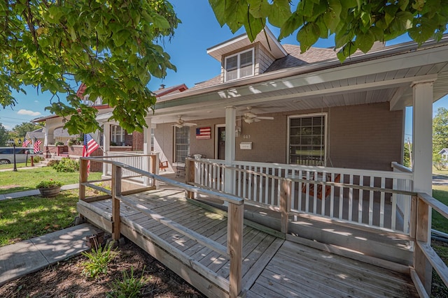 wooden deck with a porch, ceiling fan, and a lawn