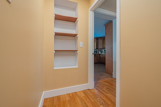 hallway featuring built in shelves and hardwood / wood-style flooring