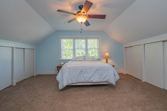 bedroom with carpet, ceiling fan, lofted ceiling, and multiple closets