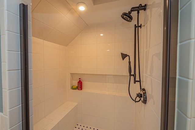 bathroom featuring lofted ceiling and tiled shower