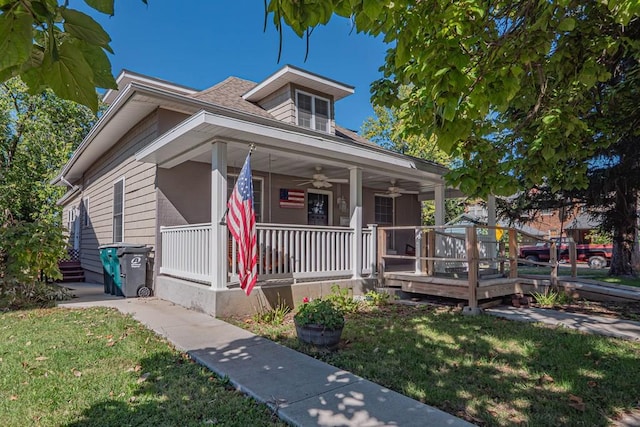 bungalow-style house with ceiling fan, covered porch, and a front lawn