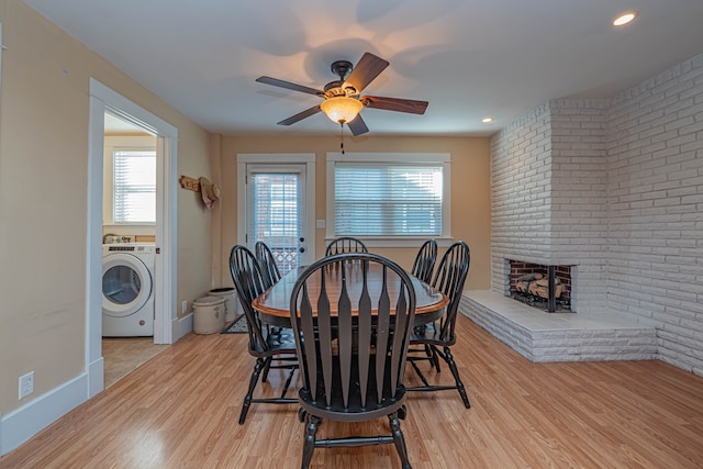 dining space with a brick fireplace, ceiling fan, light hardwood / wood-style floors, and washer / dryer