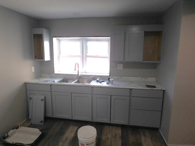 kitchen featuring light stone counters, sink, and dark hardwood / wood-style floors