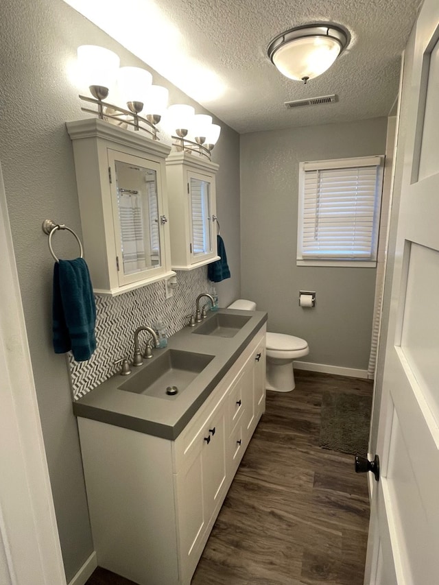 bathroom featuring hardwood / wood-style floors, a chandelier, a textured ceiling, toilet, and vanity