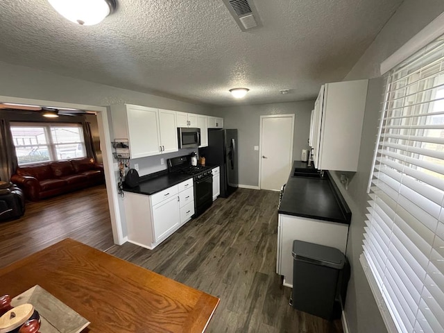 kitchen featuring white cabinetry, sink, dark wood-type flooring, a textured ceiling, and black appliances