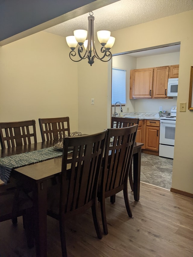 2602 Woodwinds Ct, Kirksville, MO 63501 - dining space featuring light wood-style flooring, a textured ceiling, and an inviting chandelier