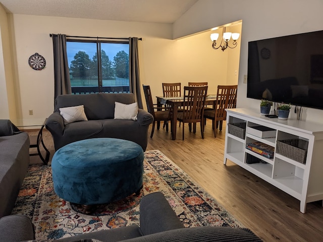 living room featuring lofted ceiling, an inviting chandelier, and wood finished floors