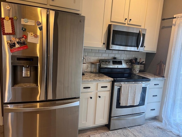 kitchen with white cabinets, decorative backsplash, and appliances with stainless steel finishes