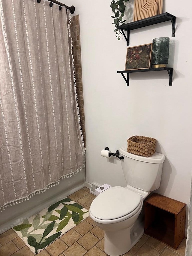 bathroom featuring tile patterned floors, toilet, and shower / bathtub combination with curtain