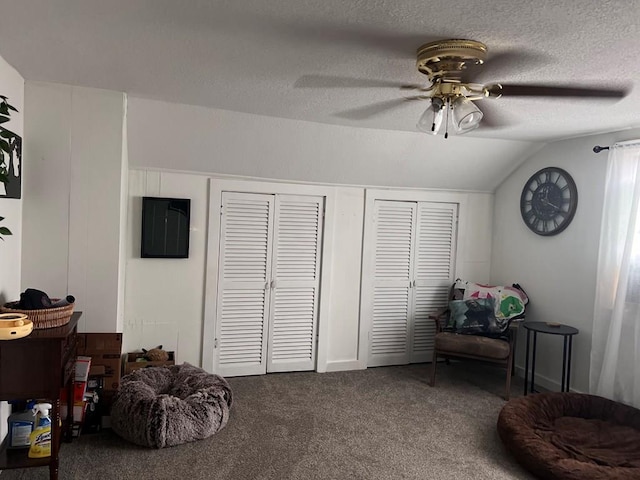 living area featuring a textured ceiling, carpet floors, vaulted ceiling, and ceiling fan