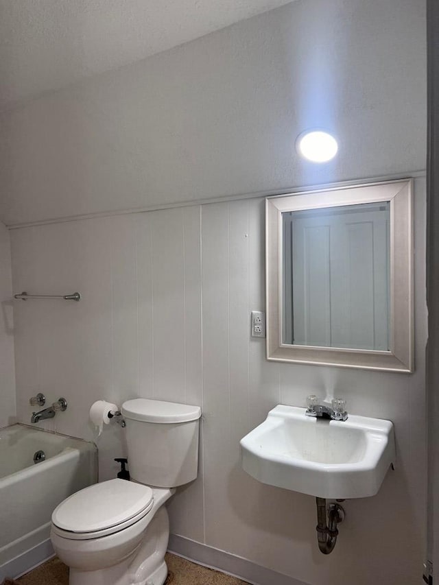 bathroom with a textured ceiling, toilet, a tub, and sink