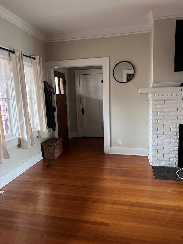 interior space with crown molding, a fireplace, a healthy amount of sunlight, and hardwood / wood-style flooring