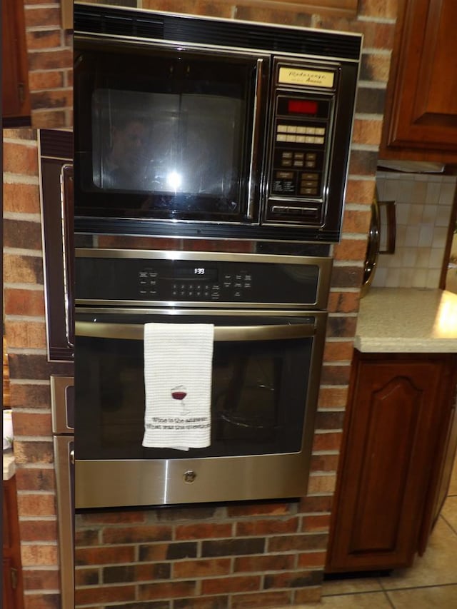 interior details featuring backsplash, black microwave, and stainless steel oven