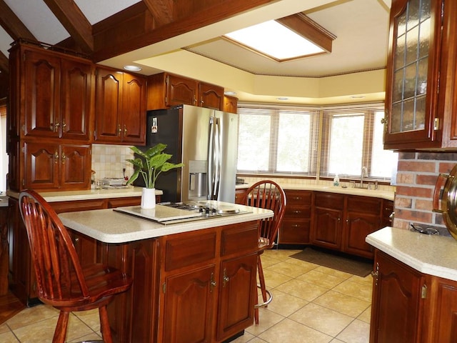 kitchen featuring light tile patterned floors, stainless steel fridge with ice dispenser, a kitchen bar, decorative backsplash, and a kitchen island