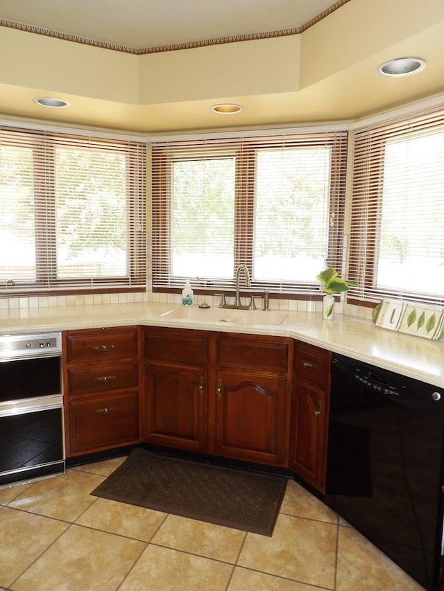 kitchen with a raised ceiling, dishwasher, light tile patterned floors, and sink