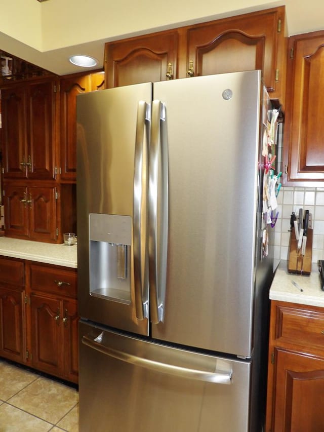 kitchen featuring decorative backsplash, light tile patterned floors, and stainless steel refrigerator with ice dispenser