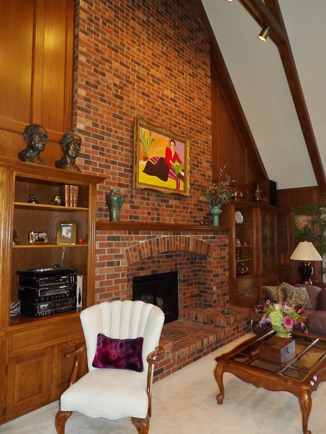 carpeted living room with a brick fireplace, high vaulted ceiling, and wooden walls